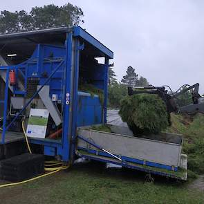 Melkveehouder Jan Veenstra heeft een wagen vers gras gemaaid. Met een shoveltje wordt gras aan de achterkant van de installatie in een voorraadbak gedeponeerd. Veenstra is zelf niet direct bij het project betrokken. Het feit dat zijn bedrijf is gekozen al