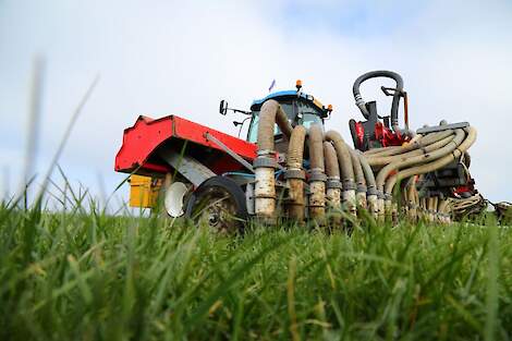 Een zodebemester rijdt mest uit in grasland.