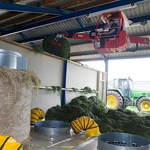 Henk Snuverink laadt met behulp van de halkraan het voorgedroogde gras in de droogbak. Op de voorgrond is het balendroogsysteem met grondbakbeluchting te zien.