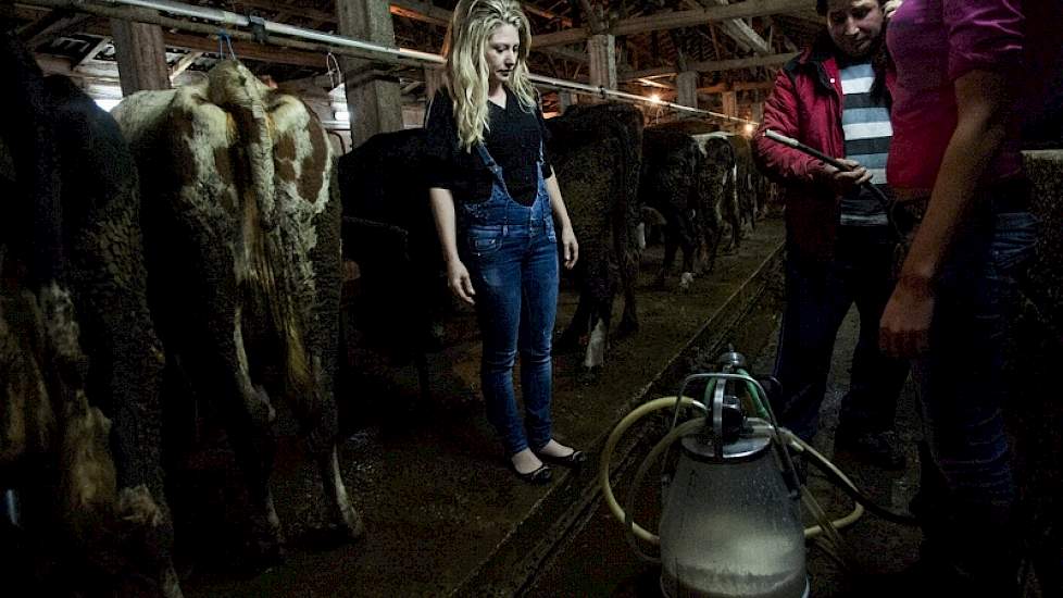 Op het bedrijf zijn twee dames aangesteld om de koeien te melken. Voor het bezoek van de journalisten hebben ze zich anders gekleed.
