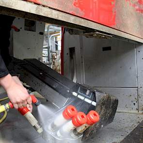 Examenkandidaat Stefan begint zijn examen met het schoonspuiten van de robotarm.